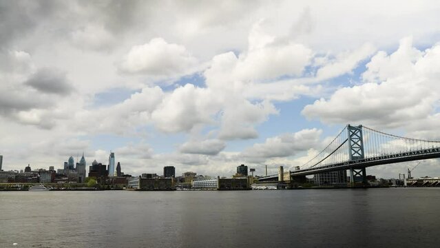 Philadelphia skyline over the calm Delaware River with the Benjamin Franklin Bridge with storm clouds