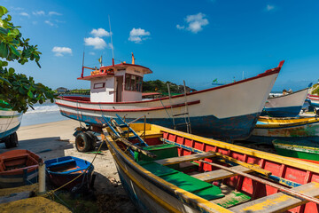 Fototapeta na wymiar Local boats on Matadeiro beach and ocean in sunny day. Colorful boats on beach in Florianopolis