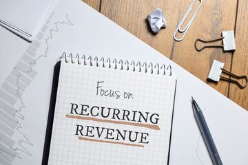 Focus on Recurring revenue business memo on notepad on desk with graph.