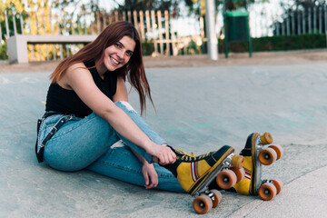 bella mujer joven andando en patines de 4 ruedas y descansando en la ciudad al atardecer en un día...