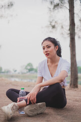 An Asian woman is exhausted and sitting after running, work out or do morning exercising. Concept of city lifestyle, healthy sport, tired and breathing, refreshment jogger sweaty.