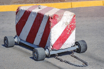 Road checkpoint. Mobile concrete barrier on wheels at a military checkpoint. Inertial anti-ram engineering device to prevent unauthorized passage of vehicles. Chain for manual control.