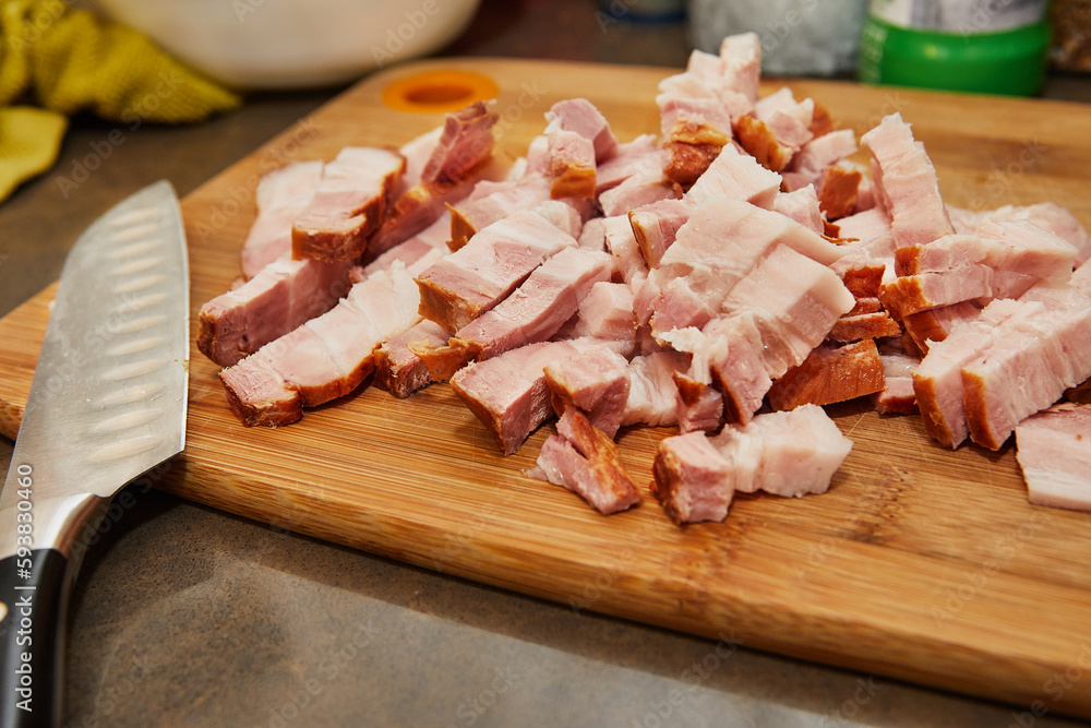 Wall mural Chef cuts bacon in the kitchen for recipe