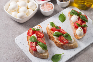Tomato, basil and mozzarella cheese fresh made caprese bruschetta. Italian tapas, antipasti with vegetables, herbs and oil on grilled ciabatta and baguette bread. Open sandwich.