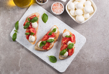 Tomato, basil and mozzarella cheese fresh made caprese bruschetta. Italian tapas, antipasti with vegetables, herbs and oil on grilled ciabatta and baguette bread. Open sandwich.