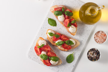 Tomato, basil and mozzarella cheese fresh made caprese bruschetta. Italian tapas, antipasti with vegetables, herbs and oil on grilled ciabatta and baguette bread. Open sandwich.