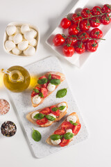 Tomato, basil and mozzarella cheese fresh made caprese bruschetta. Italian tapas, antipasti with vegetables, herbs and oil on grilled ciabatta and baguette bread. Open sandwich.