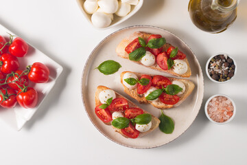 Tomato, basil and mozzarella cheese fresh made caprese bruschetta. Italian tapas, antipasti with vegetables, herbs and oil on grilled ciabatta and baguette bread. Open sandwich.