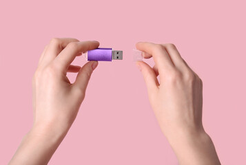 Woman holding purple USB flash drive on pink background