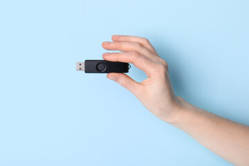 Woman holding black USB flash drive on blue background