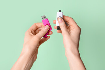 Woman holding pink and white USB flash drives on green background