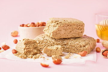 Tasty halva and peanuts on pink background