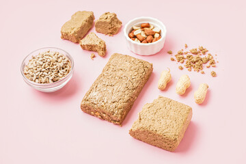Composition with tasty halva, peanuts and sunflower seeds on pink background