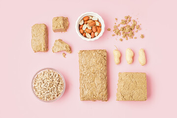 Composition with tasty halva, peanuts and sunflower seeds on pink background