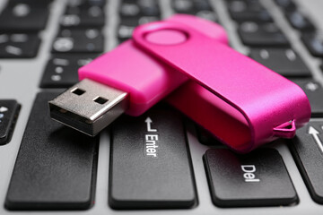 Fototapeta premium Pink USB flash drive on modern laptop, closeup