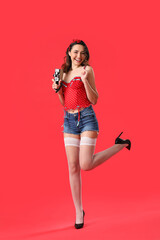 Young pin-up woman with retro video camera on red background