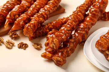 Delicious churchkhela and walnuts on color background, closeup