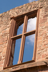 Empty window frame in a brick wall overlooking the blue sky with plenty of space for text