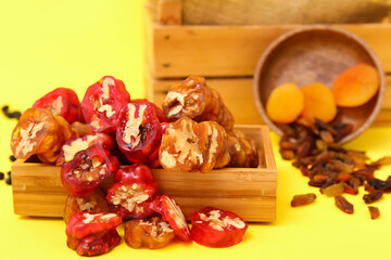 Box with delicious churchkhela and ingredients on yellow background