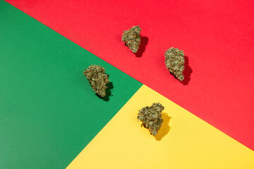 Four dry buds of medical marijuana lie on a green, yellow, red background.  Rasta colors