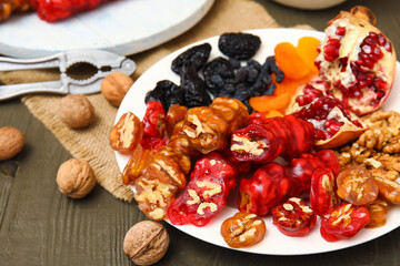 Plate with pieces of delicious churchkhela  and ingredients on wooden table