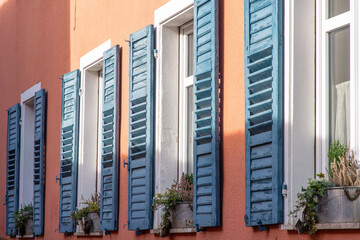 facade of a building in orange with windows with blue shutters