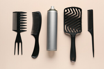 Bottle of hair spray, brush and combs on color background