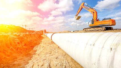 an excavator is laying a pipeline in a trench