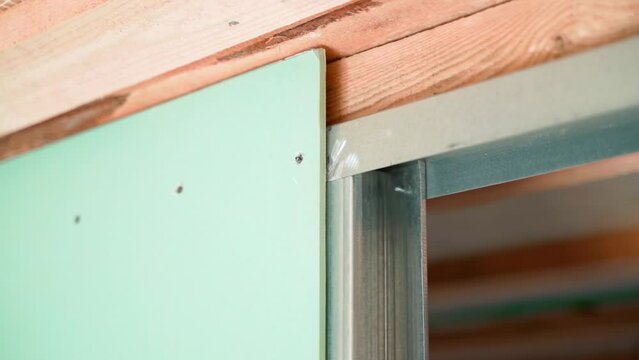 Green drywall bolted to galvanized beams, close-up. Frame partition inside the room made of metal U profile and moisture resistant drywall. Smooth camera glide