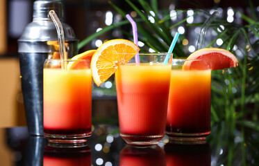 Glasses of delicious Tequila Sunrise and shaker on table