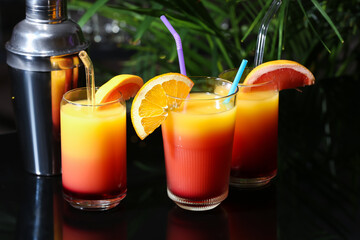 Glasses of delicious Tequila Sunrise and shaker on table