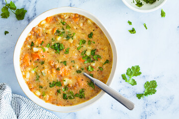 Vegan soup with potatoes, sweet potato and lentils in white bowl. Plant-based recipe.