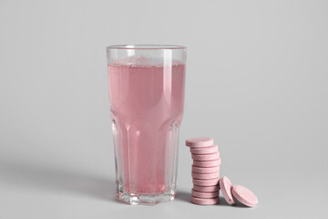 Glass with water and stack of soluble tablets on light background