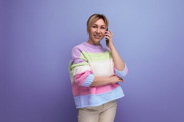 portrait of pleasant blond young woman in casual outfit smiling on purple background with copy space