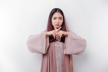 Beautiful Asian Muslim woman wearing a hijab with hand gesture pose rejection or prohibition with...