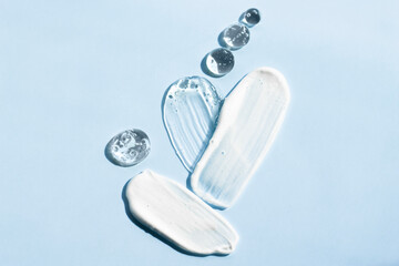 Samples of cosmetic textures in the shape of a heart on a blue background, top view. Body cream,...
