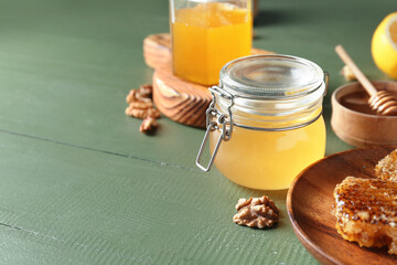 Jars of sweet honey on green wooden background