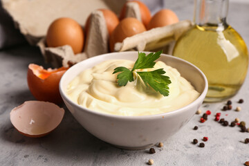 Obraz na płótnie Canvas Bowl with tasty mayonnaise sauce on grunge background, closeup