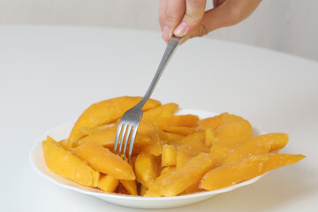 slices of yellow mango closeup photo in plate on white background
