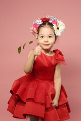 little girl in red dress with flowers in hair dress happy closeup portrait on pink background