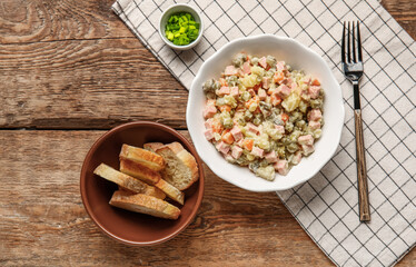 Bowl of tasty Olivier salad and bread on wooden background