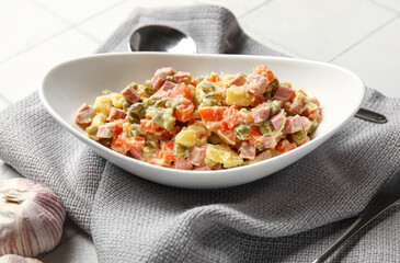 Bowl of tasty Olivier salad on white tile background