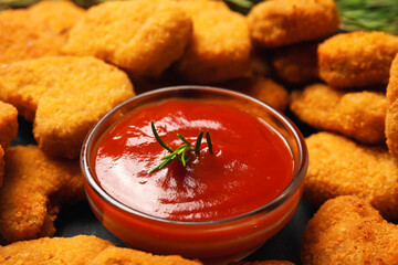 Bowl with ketchup and tasty nuggets on table, closeup