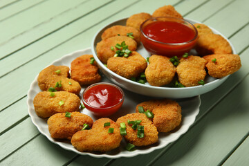 Plates of tasty nuggets with ketchup on green wooden background