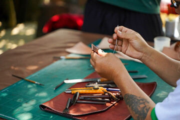 Closeup hand of leather craftsman is carefully to sew a leather belt for a customer., Leather craftsman concept.