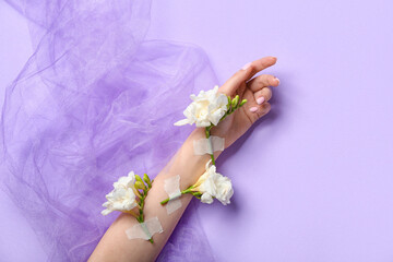 Woman with taped white flowers and veil on lilac background. Hand care concept
