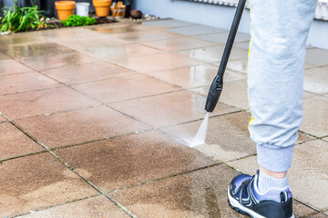 Detail of cleaning terrace with high-pressure water blaster, cleaning dirty paving stones