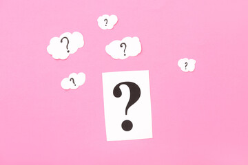 Paper and clouds with question marks on pink background