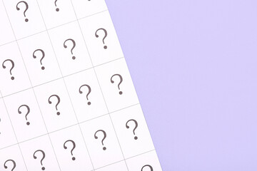 Paper with question marks on lilac background, closeup
