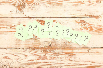 Sticky notes with question marks on white wooden background
